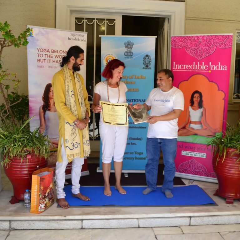 Guru Shri Siddhartha stands with a student as she receives her certificate for completing level 2 education from the Acting Ambassador of India to Greece at the Indian Embassy.